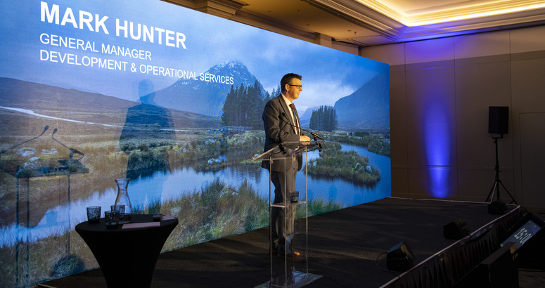 Image shows Mark Hunter, Scottish Water's Development Services General Manager at a lectern giving a speech on stage.