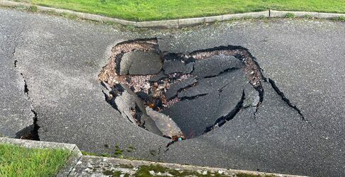 Large sinkhole breaking up tarmac on pavement