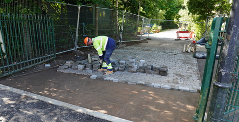A man dressed in PPE laying paving slabs on a pavement