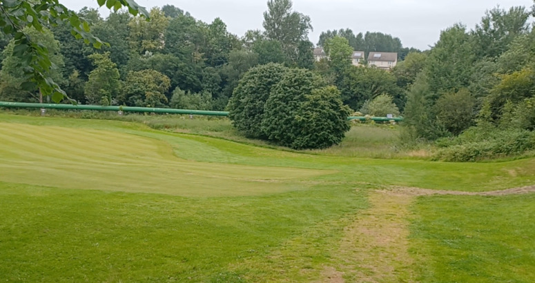 Large grassland with green pipe running above ground 