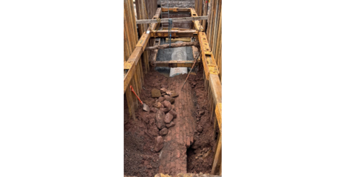 Old and replacement sewer pipes shown within an excavation