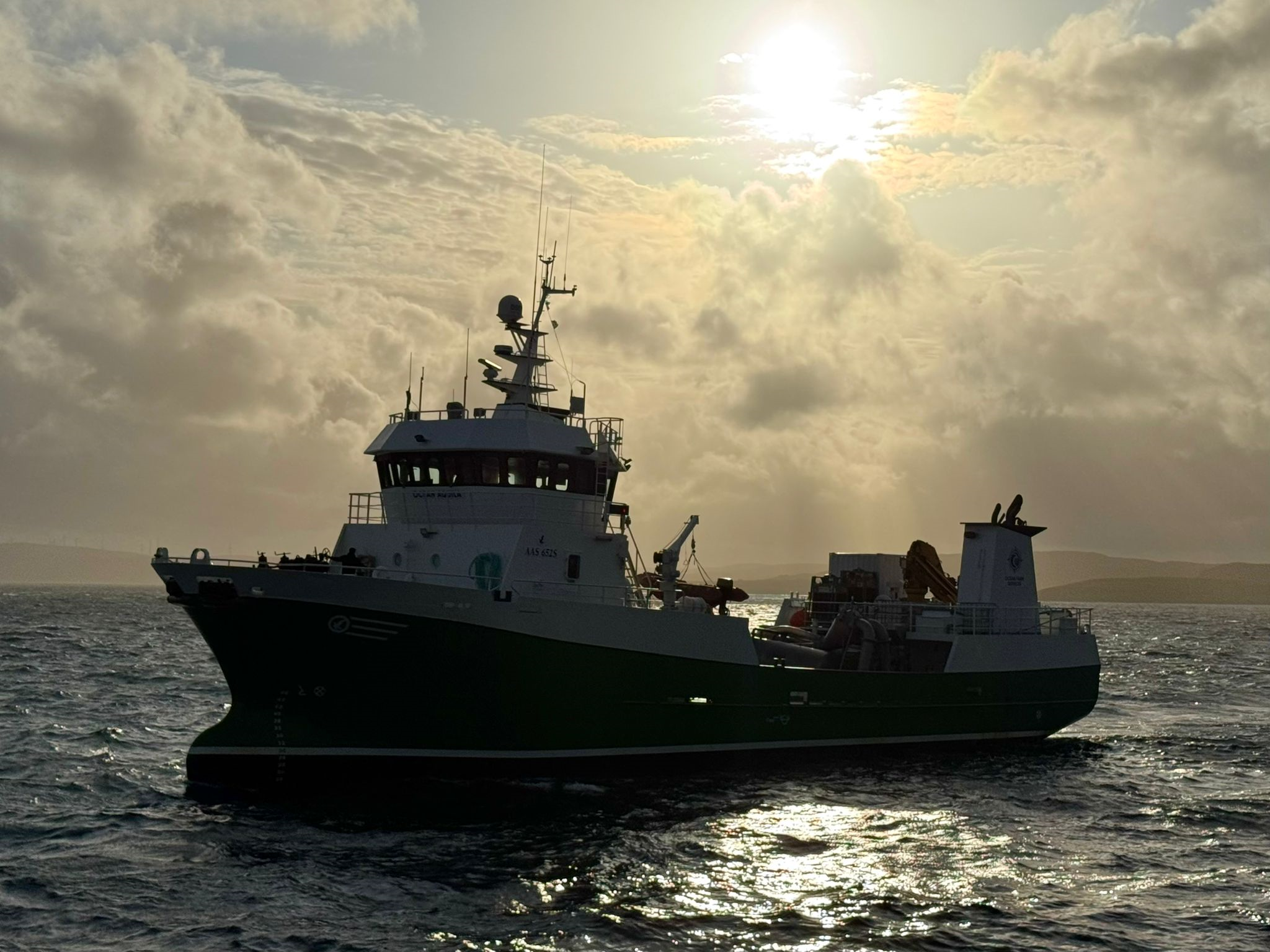 well boat on water with clouds and sun behind