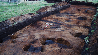 Iron Age roundhouse 1 during excavation showing arc of post settings