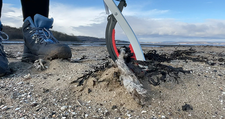 litter picker collecting wet wipes on beach