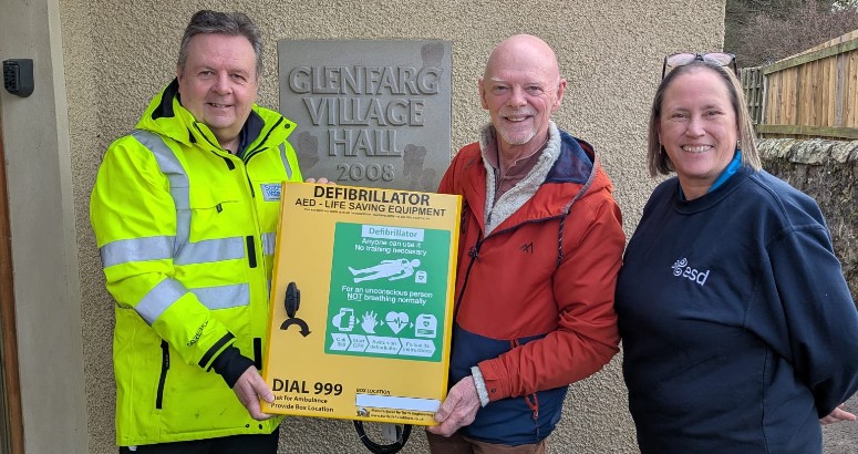 scottish water employee handing over a defib to Glenfarg community council