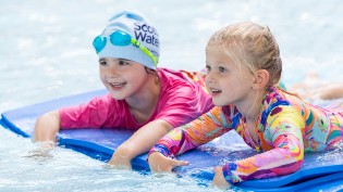 2 young girls on a float in the swimming pool enjoying their lesson