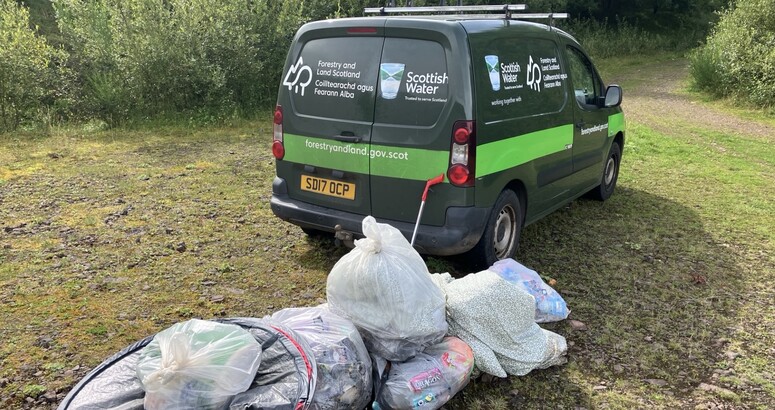 Scottish Water and Forestry Land Scotland Van with collection of litter bags beside it.