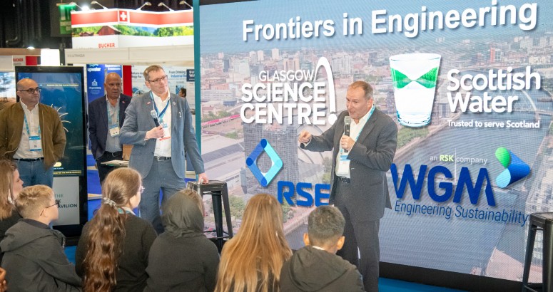 Dr Stephen Breslin, Chief Executive Officer of Glasgow Science Centre and Alex Plant, Chief Executive of Scottish Water, on stage together with microphones presenting to Ibrox Primary School