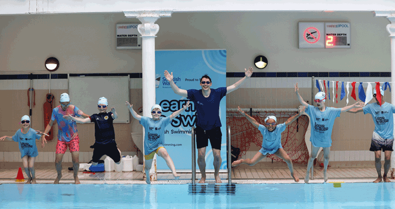 children with teacher at edge of swimming pool