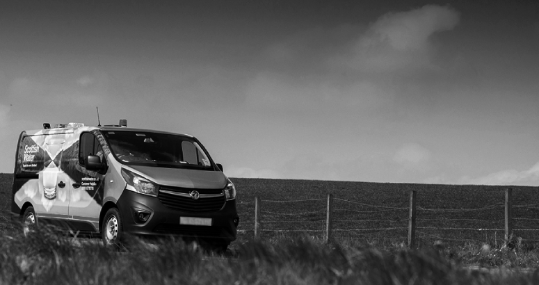 A mono picture of a Scottish Water branded van in the countryside, under cloudy skies